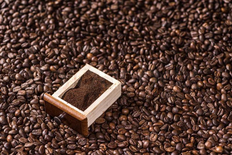 Elevated view of ground coffee in box on coffee beans background, stock photo