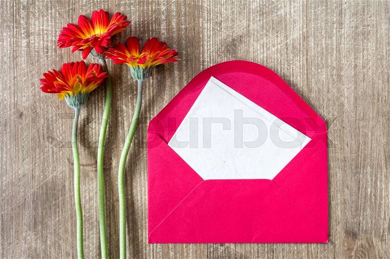 Envelope with blank letter and three gerberas on the wooden table, stock photo