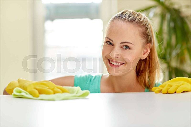 People, housework and housekeeping concept - happy woman cleaning table at home, stock photo