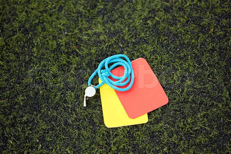 Sport, soccer and game - referee whistle and caution cards on football field, stock photo