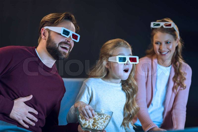 Laughing family in 3d glasses watching movie and eating popcorn on sofa, stock photo