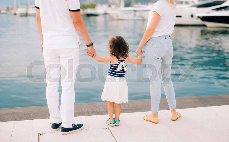 Parents with a daughter at the sea. Dad and mom are holding the baby by the hand, stock photo