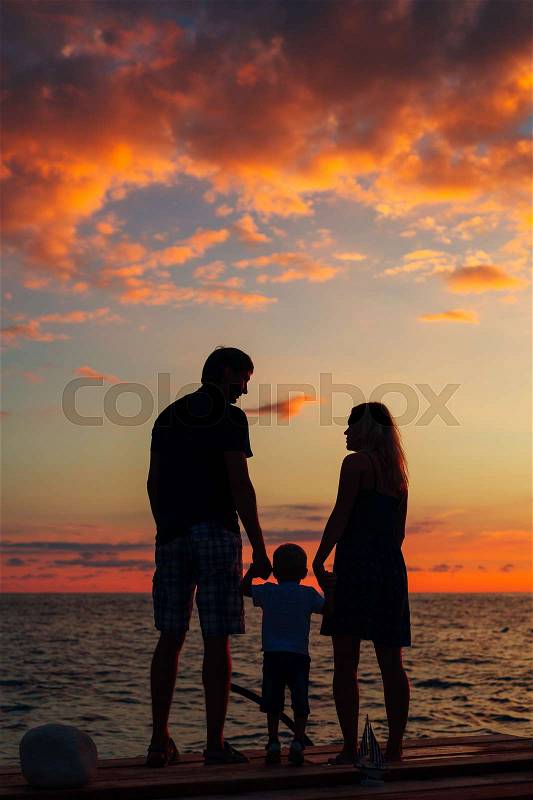 Silhouette of parents with a child at sea. Family on the beach in Montenegro, stock photo