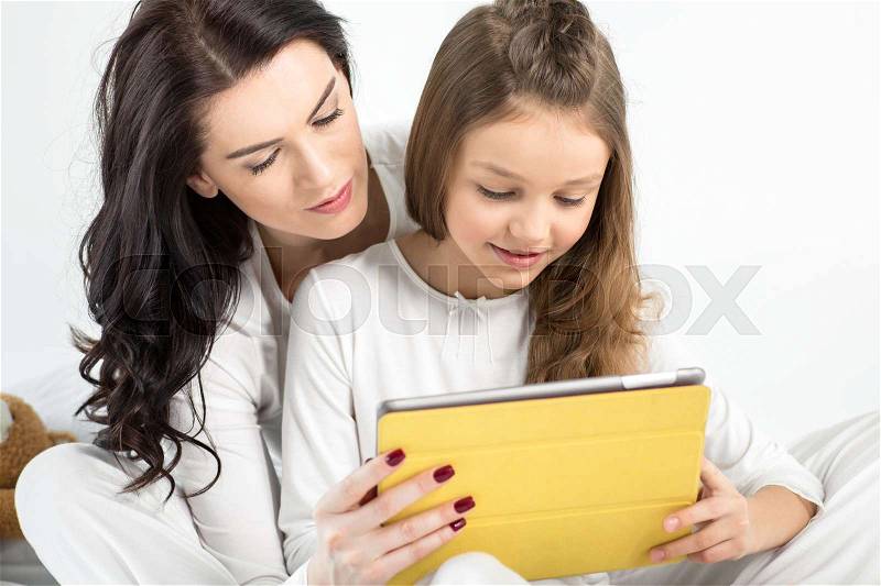 Beautiful mother and daughter using digital tablet together, stock photo