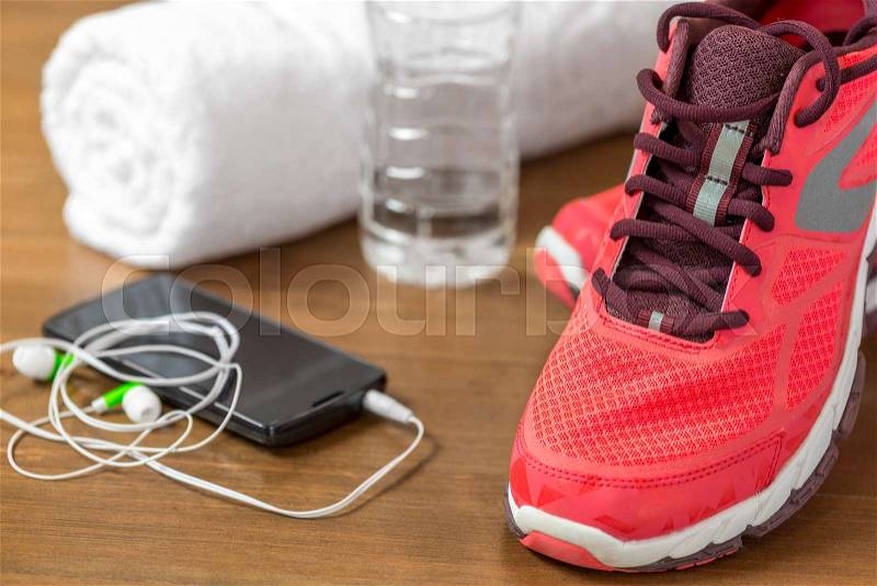 Closeup of running shoes and mobile phone headphones on a dark wooden floor, stock photo