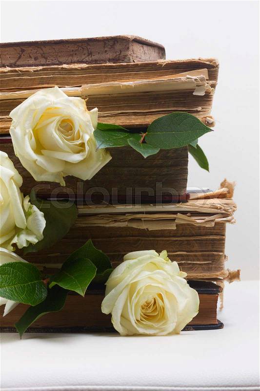 Old books pile with white flowers flowers on white background close up, stock photo