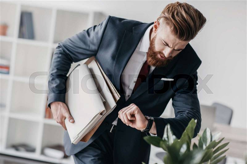 Young businessman in suit holding documents and folders in office , stock photo
