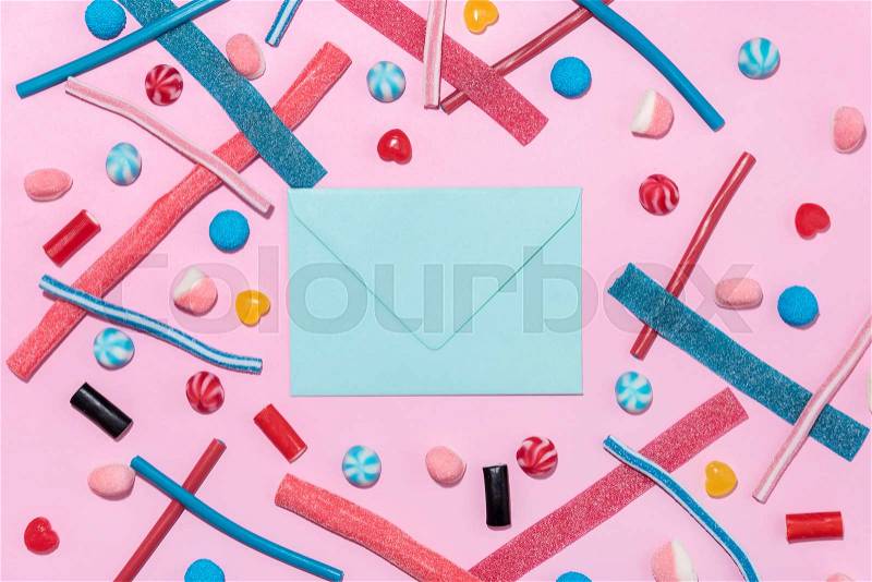 Sweet jelly licorice candy sticks and lollies with blank paper envelope isolated on blue background, stock photo