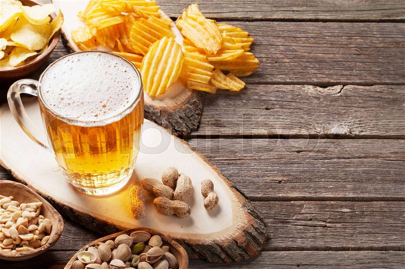 Lager beer mug and snacks on wooden table. Nuts, chips. With copy space, stock photo