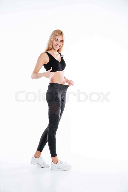 Image of pretty fitness lady standing and posing isolated over white background and make thumbs up gesture. Looking at camera, stock photo
