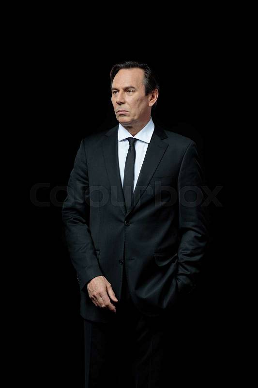 Serious mature businessman in suit looking away on black , stock photo