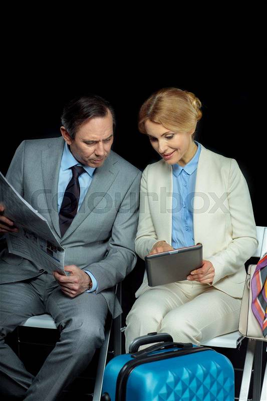 Businesswoman and middle aged businessman with newspaper and digital tablet on black , stock photo