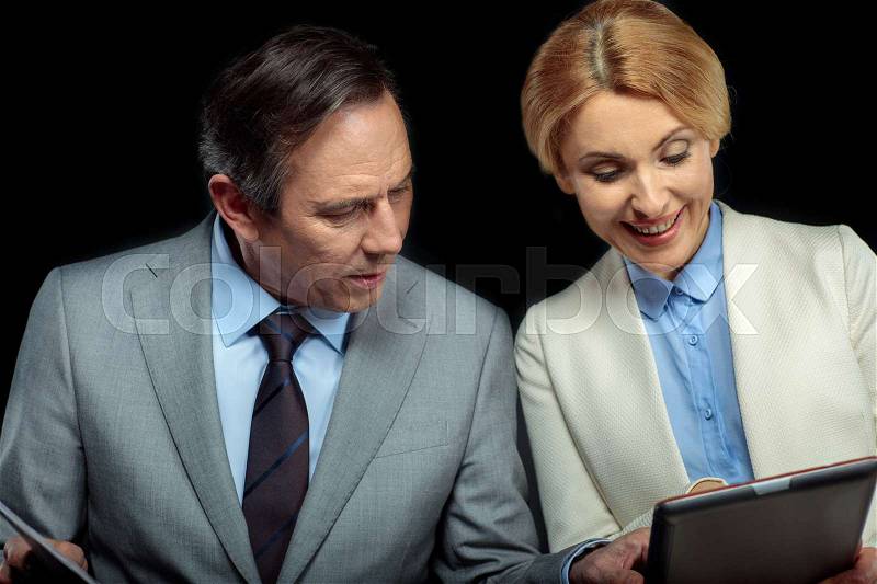 Businesswoman and middle aged businessman using digital tablet on black , stock photo