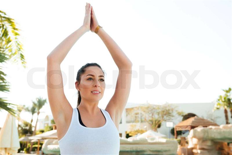 Image of attractive young fitness lady make yoga exercises outdoors near pool, stock photo