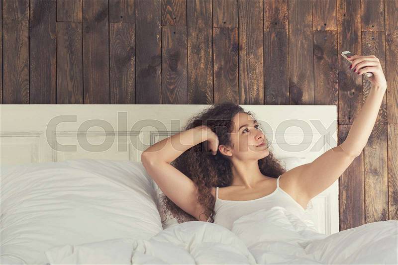 Beautiful girl make selfie lie in her bed, stock photo