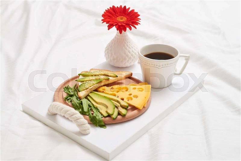 Close-up of useful breakfast rich in vitamins with tasty black tea, juicy green avocado and aromatic cheddar, salad, stock photo
