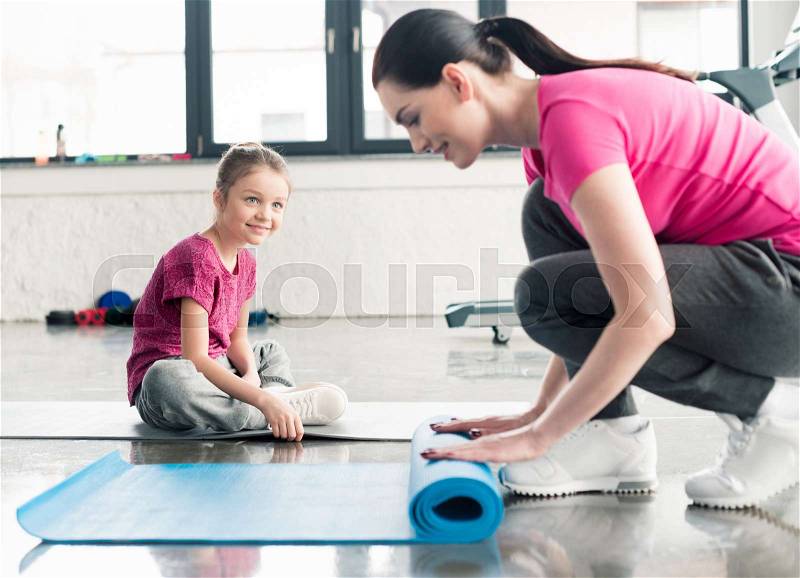 Mother and daughter in pink shirts with yoga mats in gym , stock photo