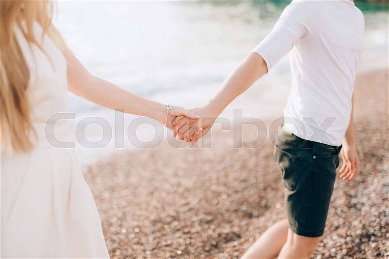 Newlyweds hold hands on the sea. Couple holding hands. Wedding in Montenegro, stock photo