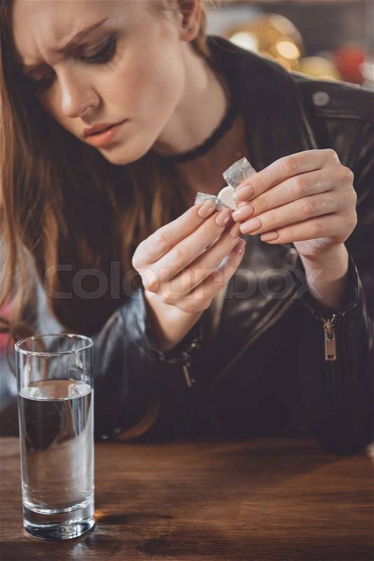 Woman with hangover with medicines in messy room after party , stock photo