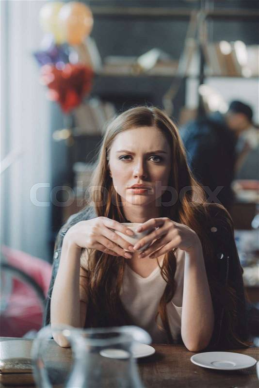 Attractive woman with coffee in messy room after party, stock photo