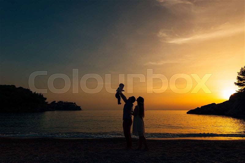 Silhouette of parents with a child at sea. Family on the beach in Montenegro, stock photo