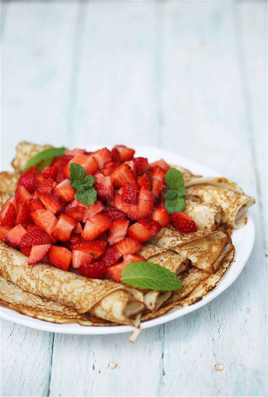 Thin ruddy pancakes rolled up with strawberries, stock photo