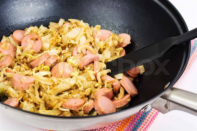 Stewed cabbage with sausages in frying pan over white background. Studio Photo , stock photo
