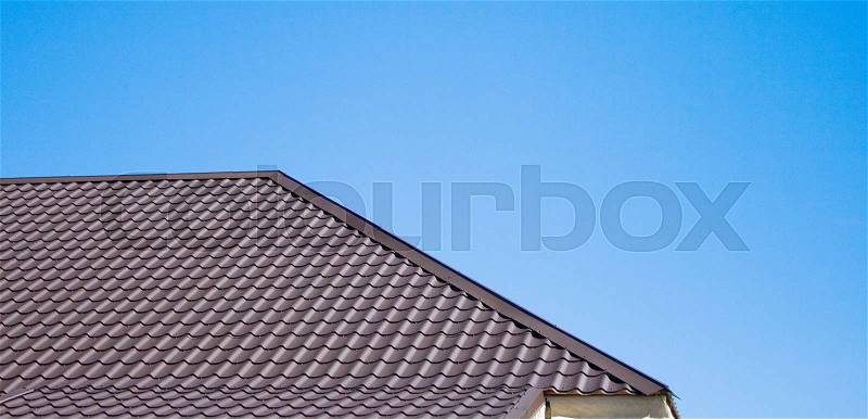 Brown roof of metal roofing on the sky background, stock photo