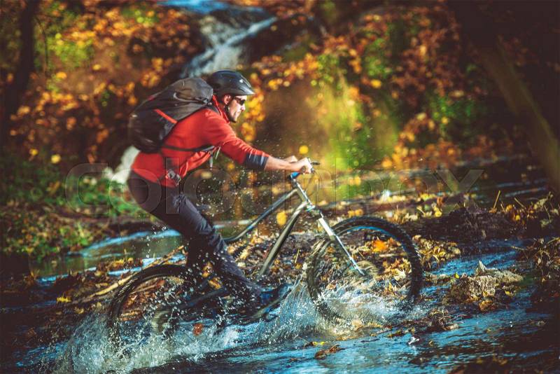 Extreme Bike Ride River Crossing in the Scenic Forest. Caucasian Biker on the Mountain Bike Fast Ride, stock photo