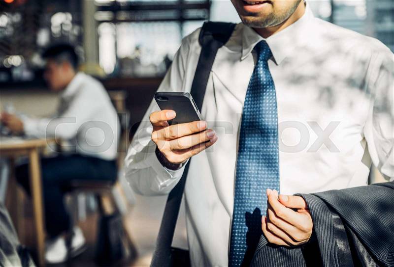Businessman using mobile phone to chatting with friend after work at corridor office building,selective focus on hand and mobile, stock photo
