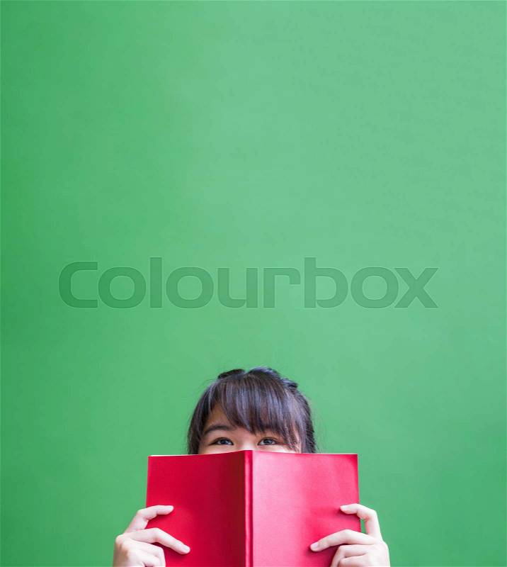 Happy young teenager girl holding red book cover face with thinking action against green vivid wall,Leave copy space upper head to adding content of design for advertising education campaign concept, stock photo