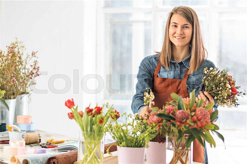 Florist at work: the young girl making fashion modern bouquet of different flowers, stock photo