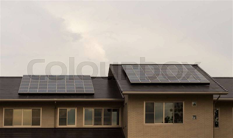 Solar panels on roof of a house with blue sky background, stock photo