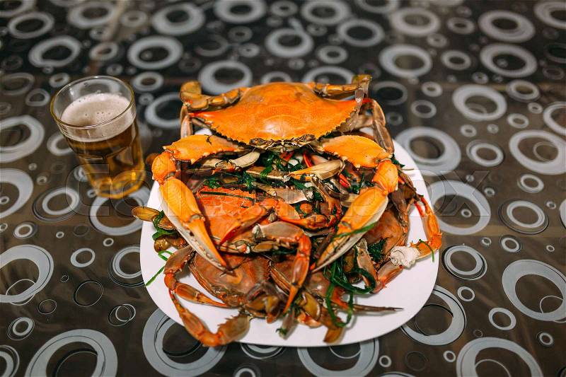 Mount cooked blue crabs in a bowl on a table with beer, stock photo