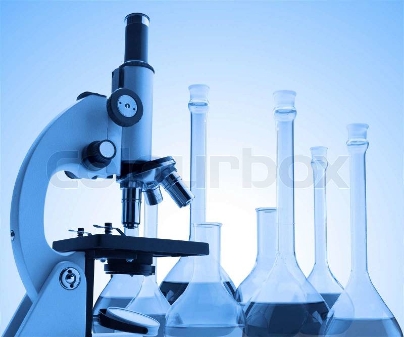 Laboratory metal microscope and test tubes with liquid toning in blue color, stock photo