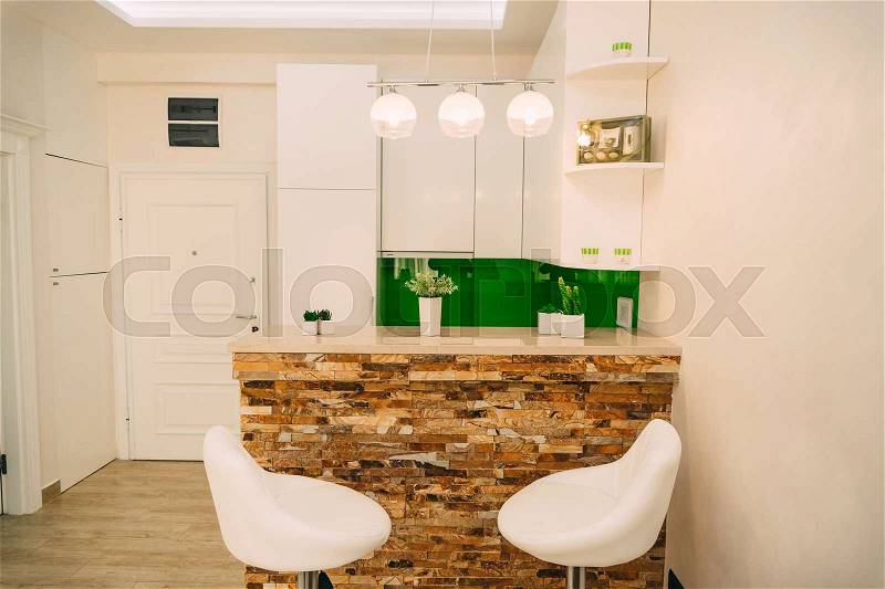 The kitchen in the apartment. The design of the kitchen room. Wooden kitchen, refrigerator, stove, dining table. Kitchen interier, stock photo