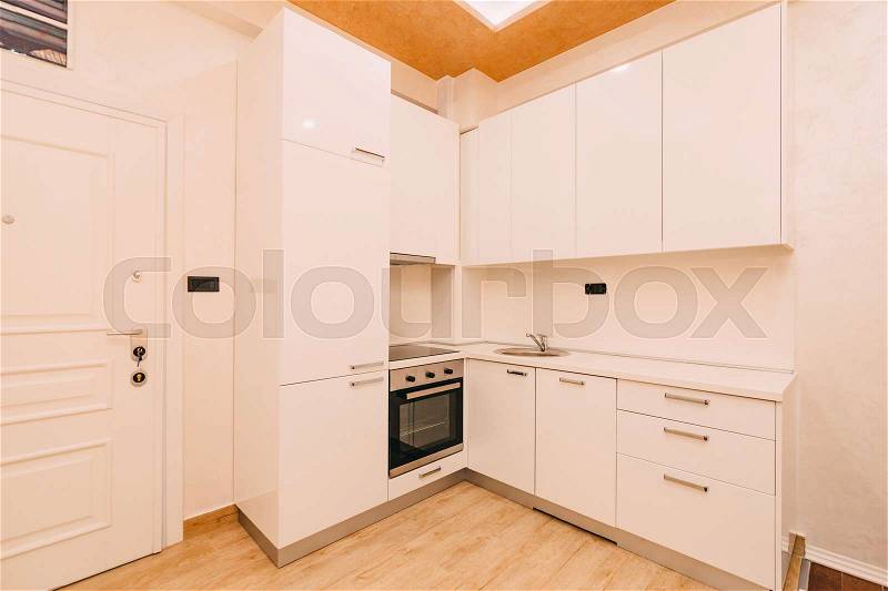 The kitchen in the apartment. The design of the kitchen room. Wooden kitchen, refrigerator, stove, dining table. Kitchen interier, stock photo