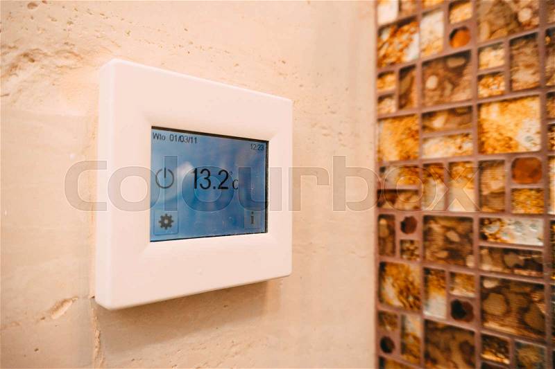 Thermostat with LCD display of the warm floor on the wall in the bathroom, stock photo