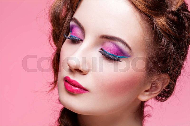Beautiful young woman with red braided hair, bright make-up over pink background. Pin up style. Copy space, stock photo