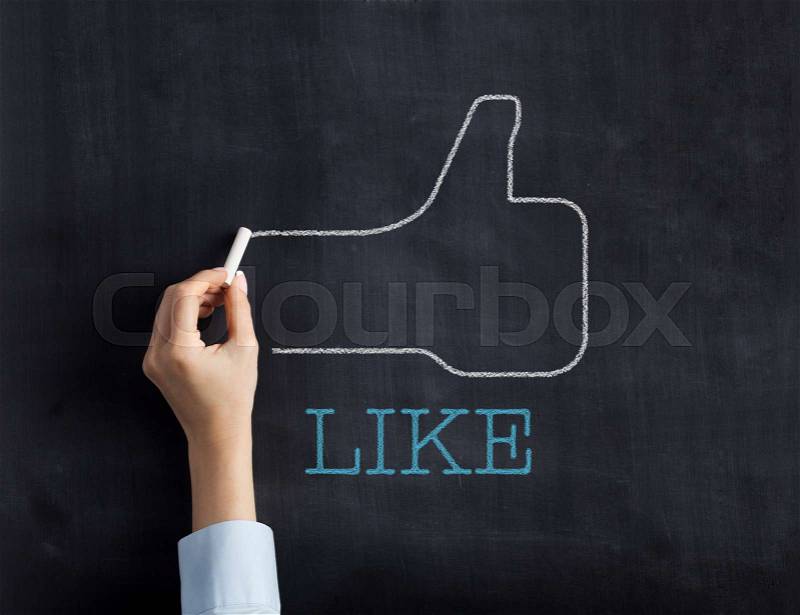 Thumbs up sketched on blackboard by businesswoman, stock photo