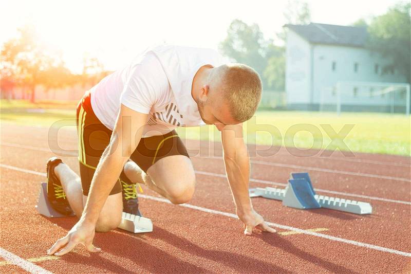 Athletic man starting evening jogging in sun rays, stock photo