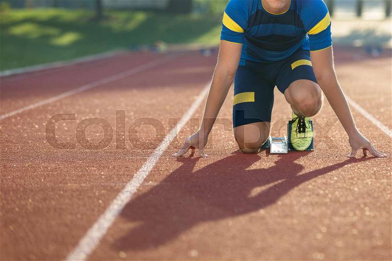 Track runner in starting position on sunny morning, stock photo