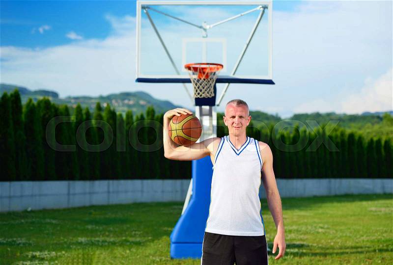 Basketball player with ball at the outdoors basket court, stock photo