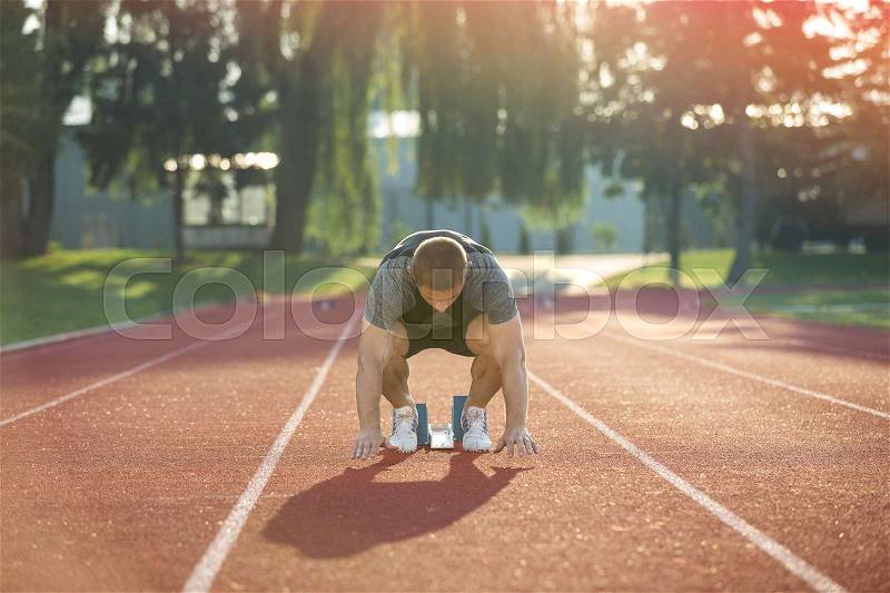 Track runner in starting position on sunny morning, stock photo