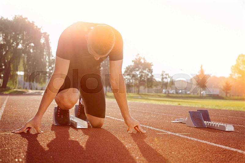 Athletic man starting evening jogging in sun rays, stock photo