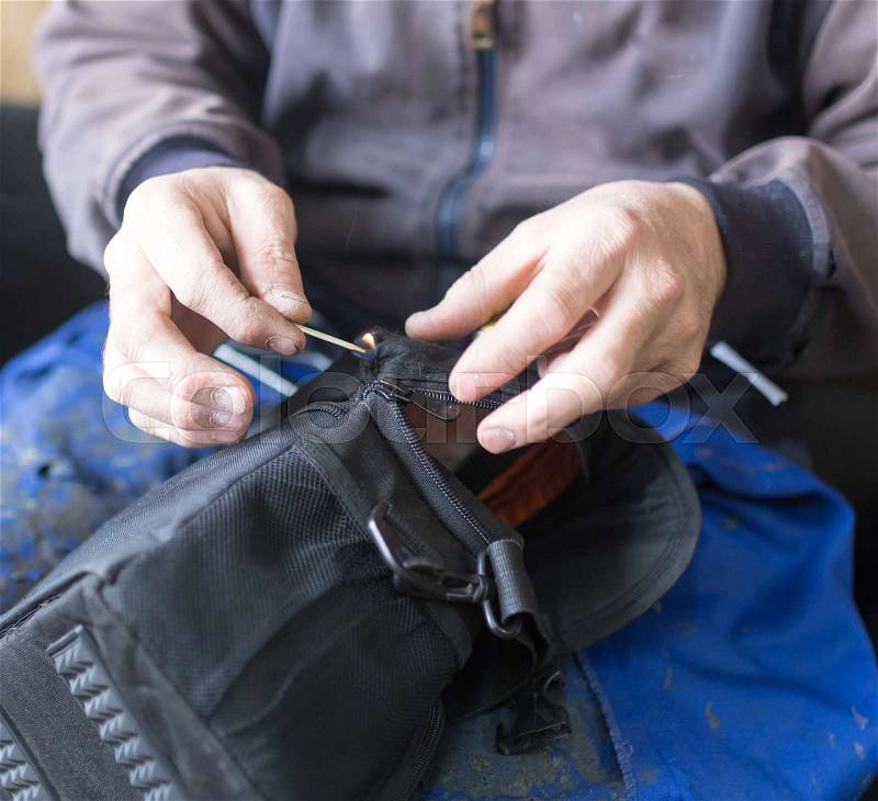 Tailor man sews up a bag in a workshop , stock photo
