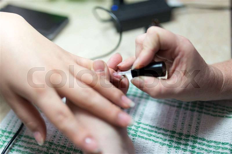 The master does a manicure of a girl in a beauty salon , stock photo