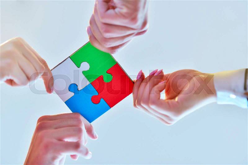 Business people group assembling jigsaw puzzle and represent team support and help concept, top view perspective at modern bright office interior, stock photo