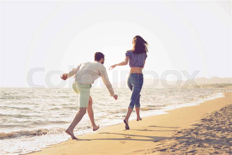 Happy young couple running on the beach, stock photo