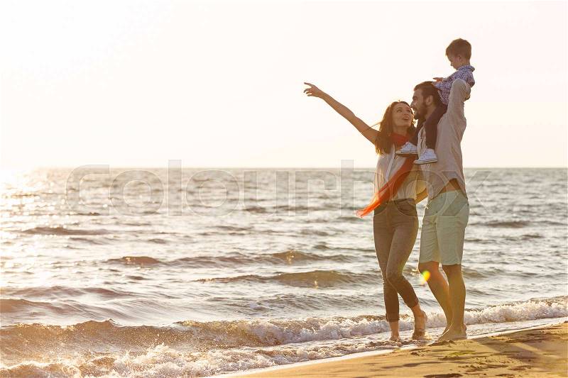 Happy young family have fun on beach run and jump at sunset, stock photo
